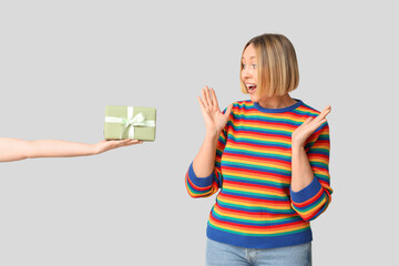 Surprised adult woman and female hand with gift box on white background