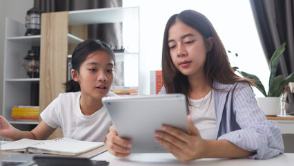 Asian siblings doing homework on a table at home