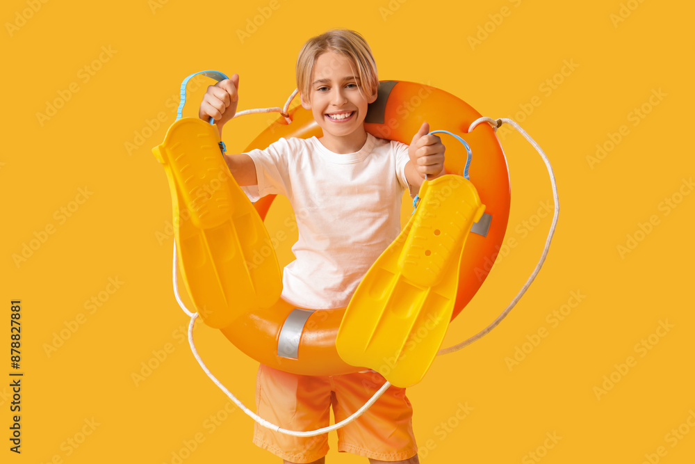 Poster Happy little boy lifeguard with ring buoy and flippers on yellow background