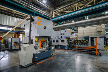 Stamping press and conveyor at metalworking factory workshop.