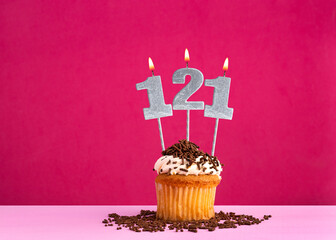 Birthday celebration with candle number 121 - Chocolate cupcake on pink background