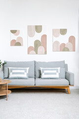 Interior of living room with comfortable sofa, coffee table and pictures on white wall
