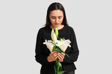 Young woman with funeral lily flowers on white background