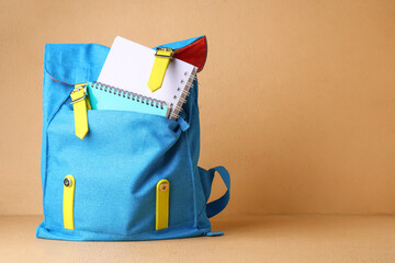 Blue backpack with notebooks on table against beige wall