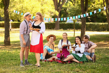 Fototapeta premium Octoberfest waitress giving tasty sausage to man outdoors