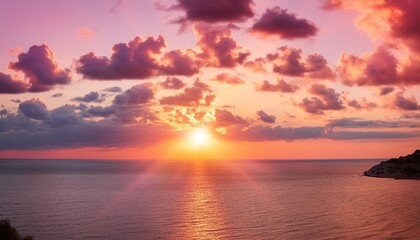 pink sunset with beautiful colorful clouds and the sun with rays over the sea
