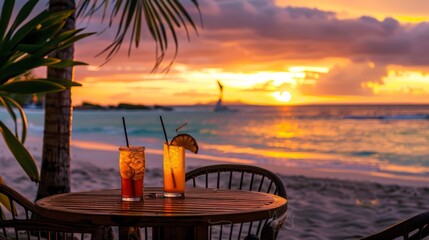 Beachside table with tropical drinks and a view of the ocean at sunset