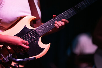 Obraz premium female musician playing guitar band at a rock show to an audience watching. sound check with a switcher in a music venue