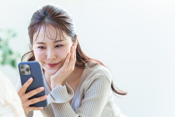 リビングでスマートフォンを使う女性