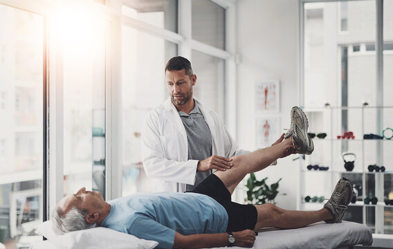 Senior man, physiotherapy and leg with stretching for join recovery, support and rehabilitation. Bed, consultation and patient with exercise in help for knee pain, inflammation and joint strength