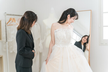 Naklejka premium 結婚式の準備でウェディングドレスの衣装合わせをするアジア人女性（試着・フィッティング） 