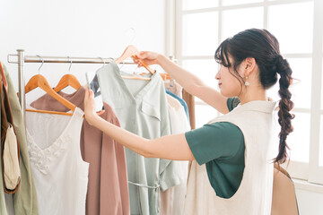 アパレルショップで洋服を買い物・ショッピングする若いアジア人女性
