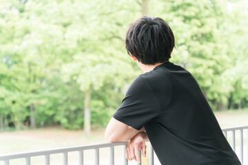 公園で景色を眺めるスポーツウェア姿の若いアジア人男性  © buritora