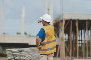 Asian man architect holds blueprint with skyscraper background, Asian male architect builder engineer design working planning confident outdoors in construction site.