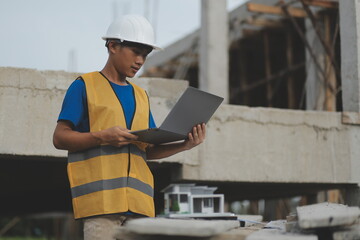 Young handsome asian civil engineer holding tablet looking forward and thinking, planning on construction building background. Evolution construction concept.