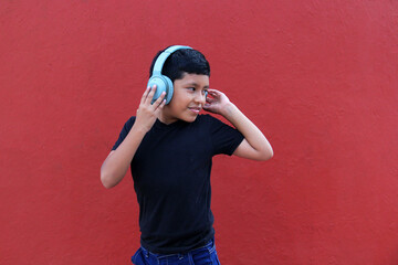 9-year-old dark-skinned Latino boy uses noise-isolating headphones due to the sensitivity caused by...
