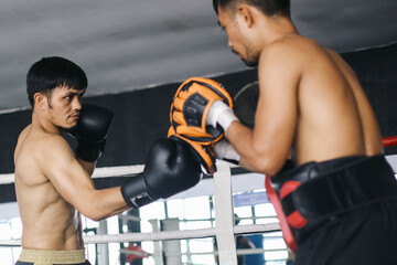 Two Asian Fighters Man Practices Together Wearing Boxing Gloves And Punching Pad In Boxing Ring
