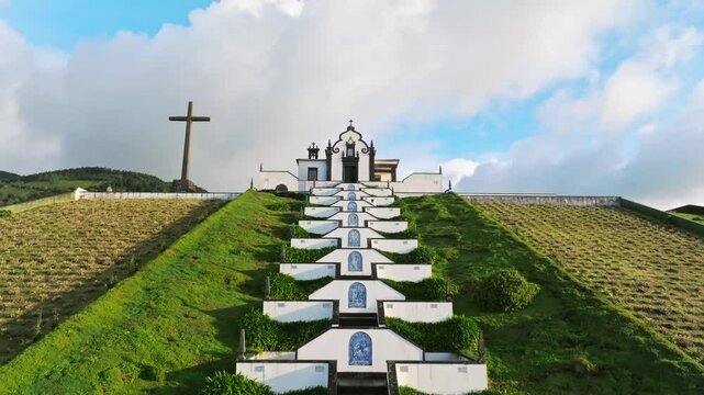 Drone zooms Old european white chapel architecture, green meadow Azores Portugal