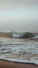 A wave crashes on the sandy beach as the sun rises