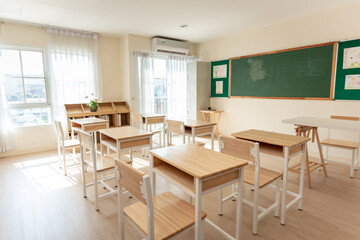 Shot of empty classroom with chairs under desks in elementary. 