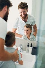 Obraz premium Bathroom, dad and child washing hands with support, smile and teaching healthy hygiene in mirror. Cleaning, happy boy and father getting ready with routine, morning wellness and skincare in home.