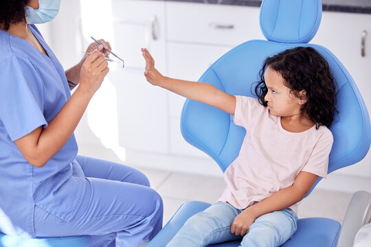 Stop, scared and dentist with child patient for tooth extraction in clinic with consultation. Fear, dentistry and upset girl kid with pediatric orthodontist for cavity removal with equipment.