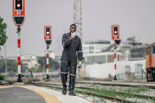 A railway signal maintainer communicates via radio while walking along the tracks