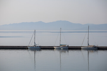 Obraz premium three white boats with masts docked in the harbor on a calm sea