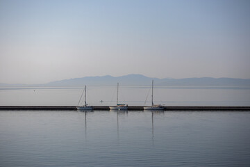 Fototapeta premium three white boats with masts docked in the harbor on a calm sea