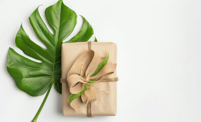A gift wrapped in natural paper and burlap ribbon with a leaf, representing sustainable packaging.