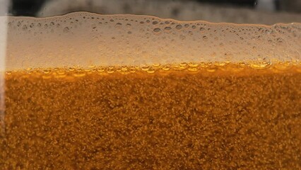 Beer bubbles rising in a glass close up. Beer foam in a glass, light craft lager beer