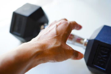 ダンベルを掴もうとしている女性の手のクローズアップ