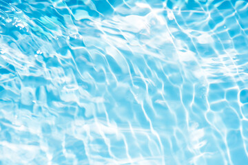 Blue water with ripples on the surface. Defocus blurred transparent blue colored clear calm water surface texture with splashes and bubbles. Water waves with shining pattern texture background.