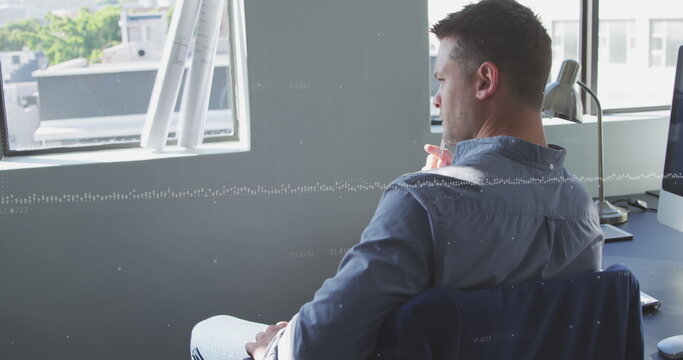 Image of data processing against thoughtful caucasian man sitting on his desk at office