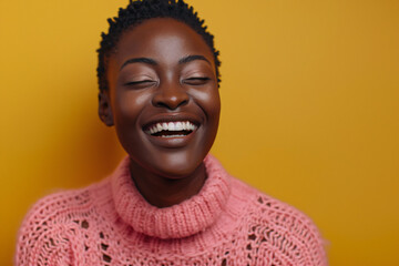 Photo of a black woman laughing heartily with her eyes closed, wearing a pink sweater isolated on a yellow background, in a studio shot, high resolution photography.