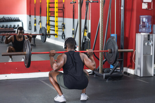 A fit African American man performs a squat at the gym