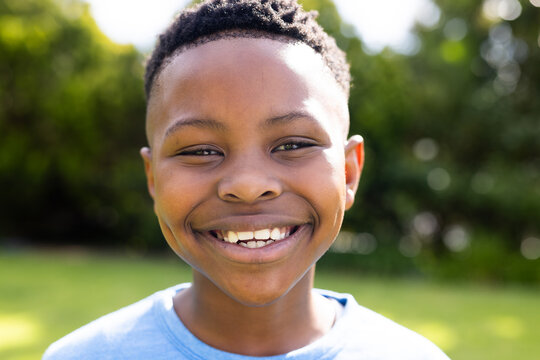 African American boy smiles brightly outdoors, with copy space unaltered