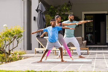 African American father practices yoga outdoors with his son and daughter