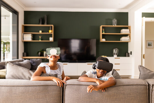 Teenage biracial brother and sister enjoy VR headsets at home