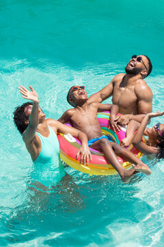 Diverse family enjoys a sunny day in the pool, with copy space