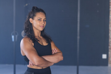 Young biracial woman stands confidently at the gym