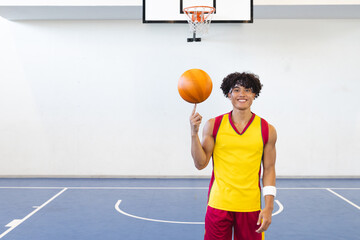 Young biracial man spins a basketball on his finger at an indoor court