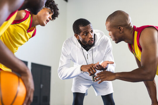 Coach strategizes with basketball players during a timeout - Powered by Adobe