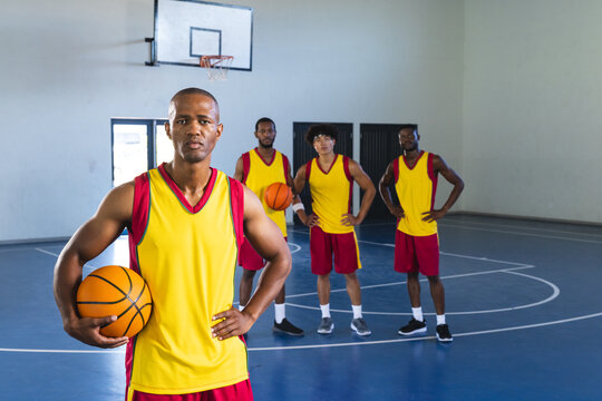 African American man holds a basketball in an indoor court