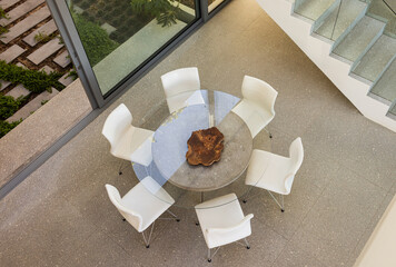 A modern home interior features a round glass table and white chairs