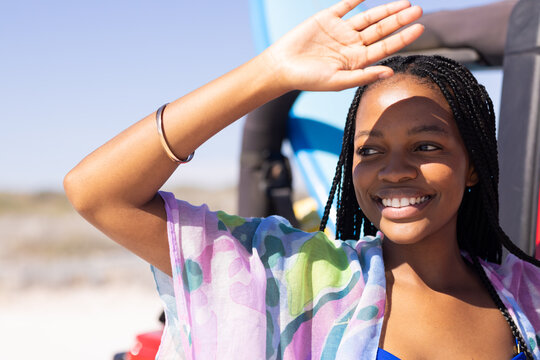 Young African American woman shields her eyes from the sun on a road trip