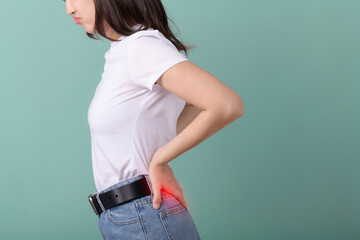 Coccyx pain. adult female with muscle pain on green background. asian woman having back body ache...