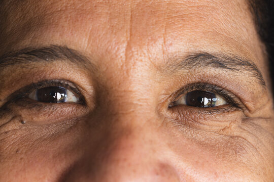 Portrait close up of brown eyes of happy senior biracial woman smiling at home - Powered by Adobe