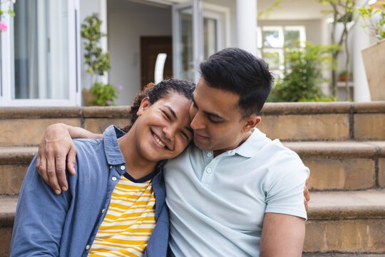 Biracial couple enjoys a warm embrace outdoors, unaltered