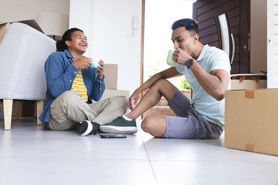 Young biracial man and Middle Eastern man, a gay couple, enjoy a coffee break at home